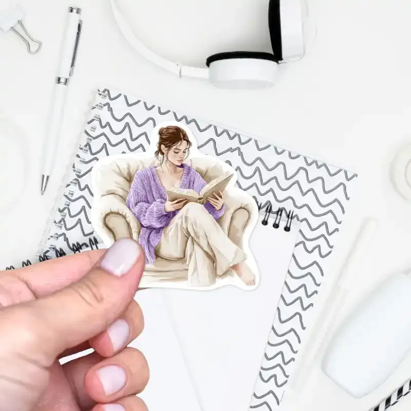 Samolepka Žena při čtení knihy, v béžových a pastelově fialových tónech.